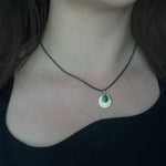 Australian Black Opal and 9ct Gold Pendant with engraved detail hangs from an oxidised sterling silver chain, and is worn by a person with an asymmetrical black top, worn on the shorter option on the chain.