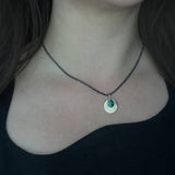 Australian Black Opal and 9ct Gold Pendant with engraved detail hangs from an oxidised sterling silver chain, and is worn by a person with an asymmetrical black top, worn on the shorter option on the chain.