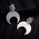 Sterling Silver Lunar crescent moon earrings on a dark wooden surface.