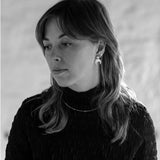 Black and white portrait of a woman with long hair wearing the Lunar Stud earrings and Pyrite Choker necklace.
