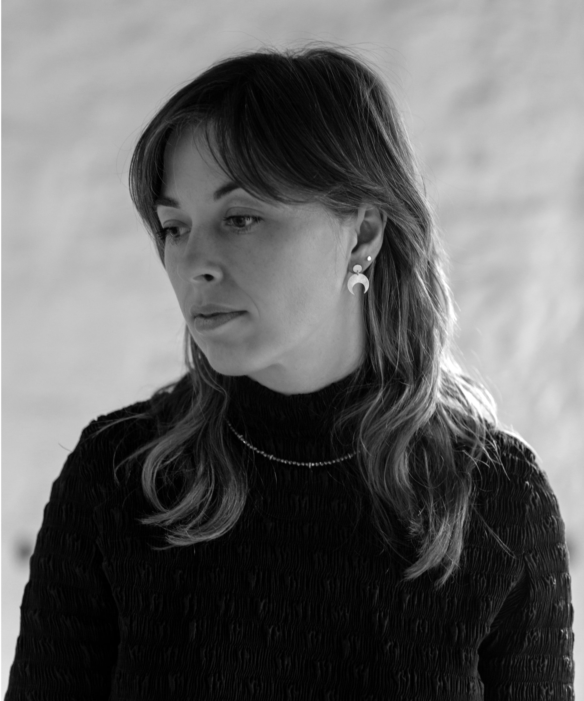 Black and white portrait of a woman with long hair wearing the Lunar Stud earrings and Pyrite Choker necklace.