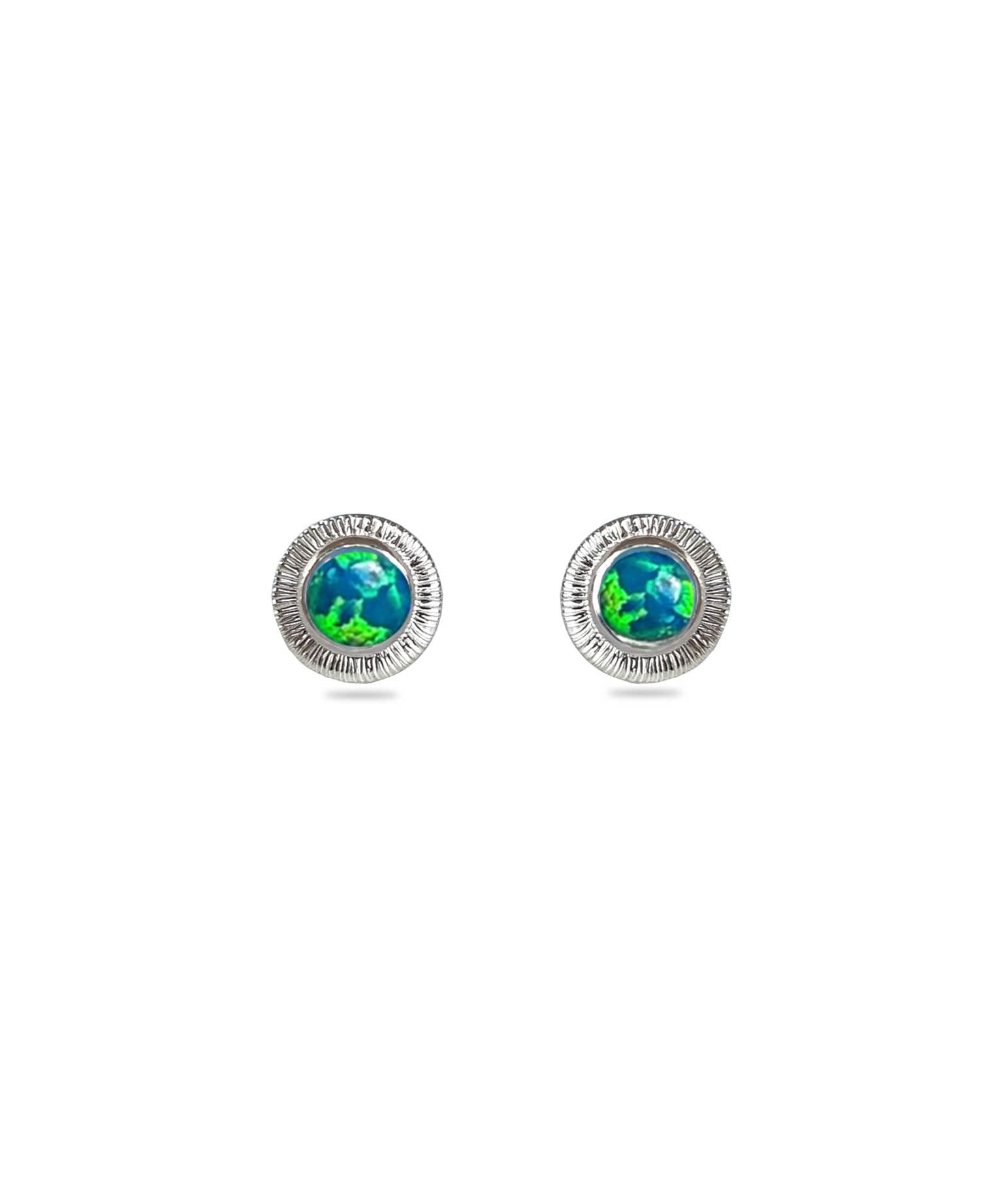 A pair of round stud earrings featuring a textured silver-tone outer ring and a central cabochon inlay depicting the globe of Earth in vibrant green and blue tones, set against a plain white background.