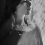Black and white portrait of a woman wearing the Luna Crescens necklace by Emily Eliza Arlotte, featuring a crescent moon.