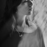 Black and white portrait of a woman wearing the Luna Crescens necklace by Emily Eliza Arlotte, featuring a crescent moon.