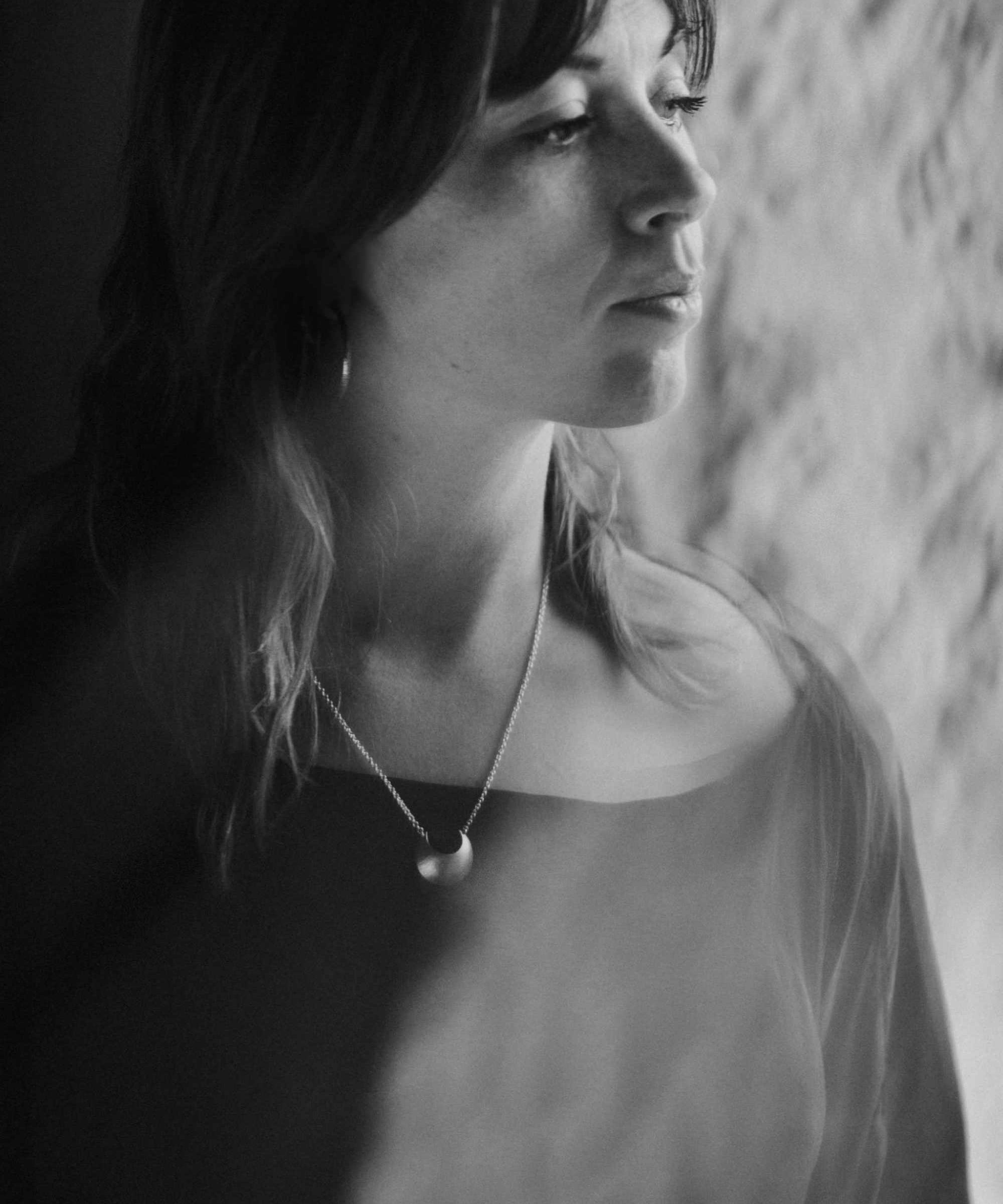 Black and white portrait of a woman wearing the Luna Crescens necklace by Emily Eliza Arlotte, featuring a crescent moon.
