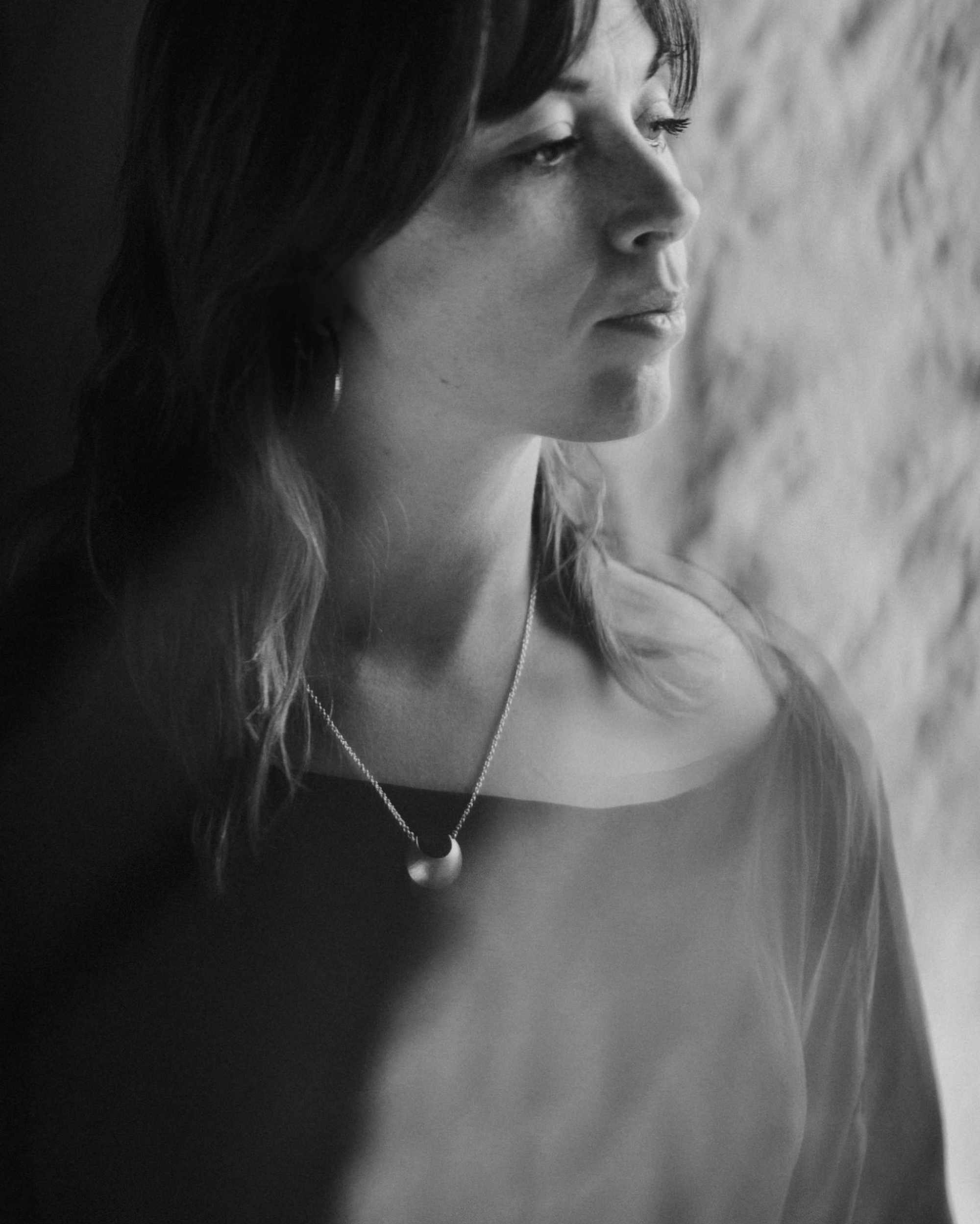 Black and white portrait of a woman wearing the Luna Crescens necklace by Emily Eliza Arlotte, featuring a crescent moon.