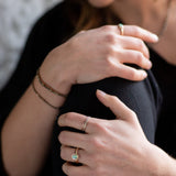 Close-up of a person's hands wearing an Australian Gold Opal Ring, and The Trinity Stack Rings.
