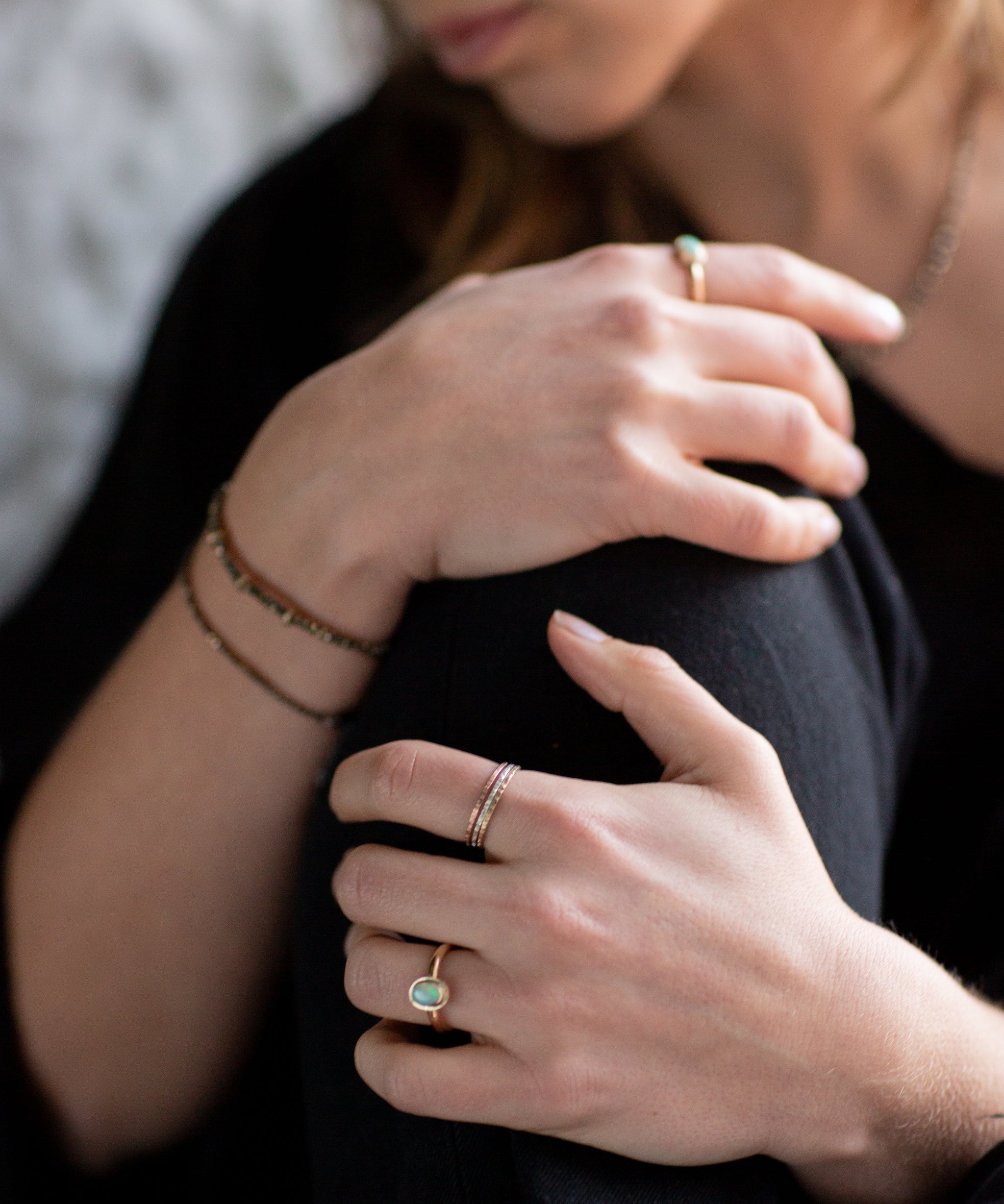 Close-up of a person's hands wearing an Australian Gold Opal Ring, and The Trinity Stack Rings.