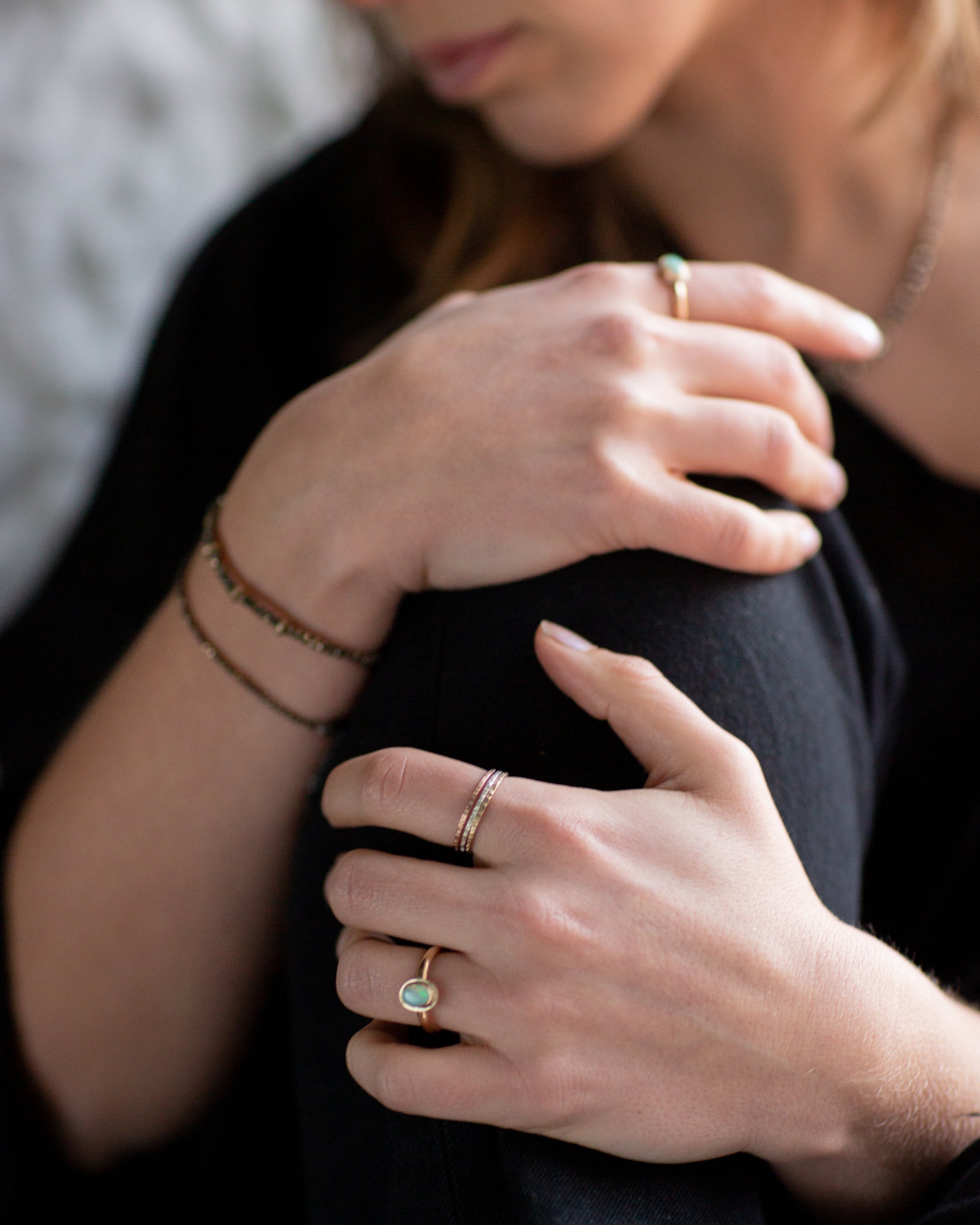 Close-up of a person's hands wearing an Australian Gold Opal Ring, and The Trinity Stack Rings.