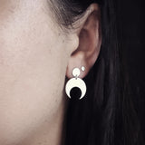 Close-up of an ear wearing the Sterling Silver Lunar stud earrings with a dark background. These earrings feature a textured crescent moon design. 