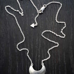 Sterling Silver Luna Crescens necklace featuring a crescent moon on a dark wooden surface