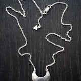 Sterling Silver Luna Crescens necklace featuring a crescent moon on a dark wooden surface