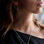 Close-up of a person wearing a Sterling Silver Luna Crescens necklace featuring a crescent moon by Emily Eliza Arlotte
