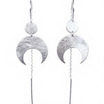 Lunar Thread Earrings on a white background. These sterling silver earrings feature a textured disc and crescent moon hanging from a hook and fine chain fitting.