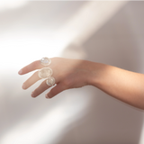 Hand wearing three Quartz Prescience rings handmade by Emily Eliza Arlotte with a soft light background. Photo by Cassie Sullivan.