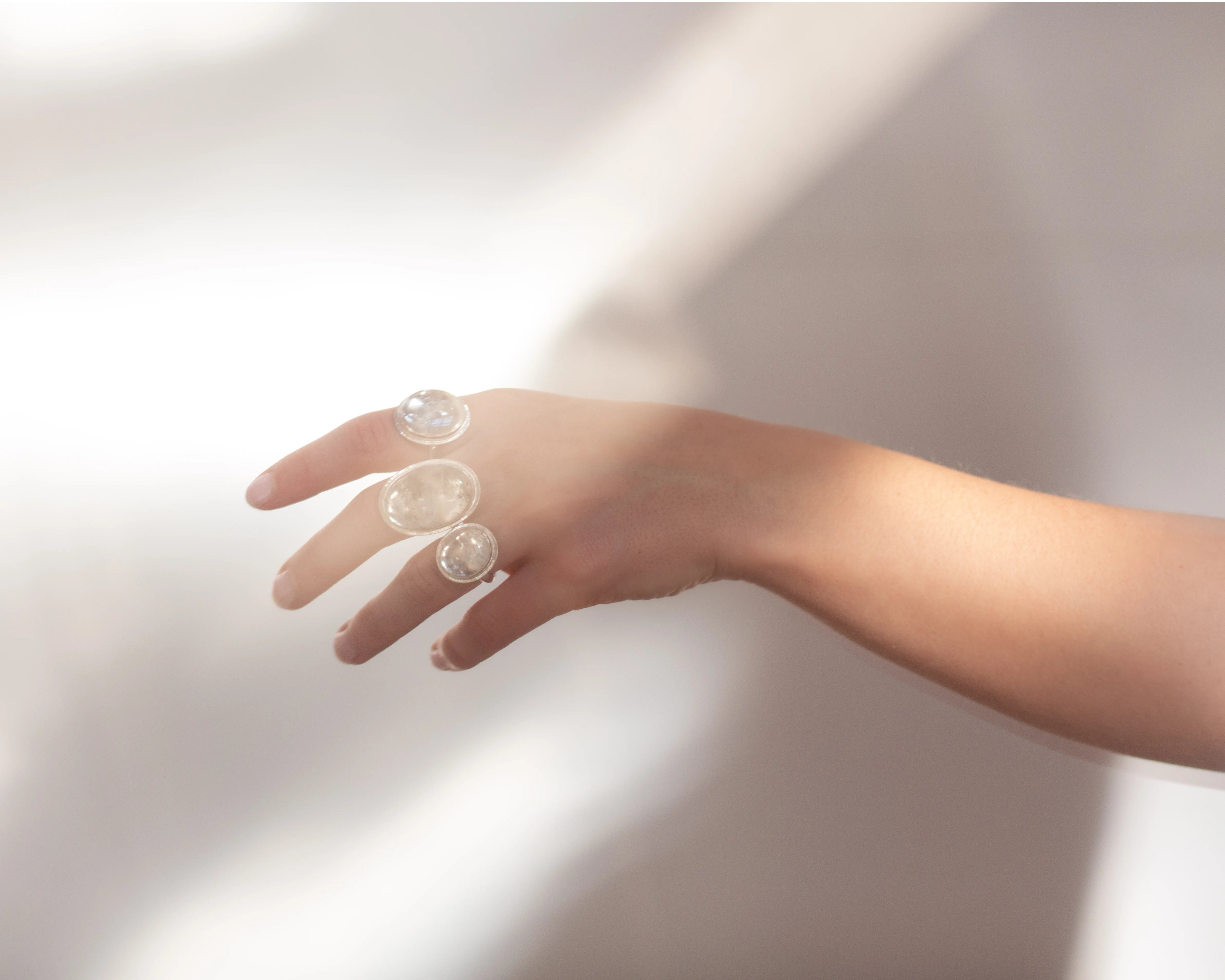 Hand wearing three Quartz Prescience rings handmade by Emily Eliza Arlotte with a soft light background. Photo by Cassie Sullivan.