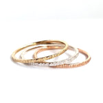 The Trinity Stack Rings, showing they are three separate rings, on a white background. These rings are a combo of Yellow Gold, Sterling Silver, and Rose Gold, and have a textured organic finish.