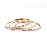 The Trinity Stack Rings, showing they are three separate rings, on a white background. These rings are a combo of Yellow Gold, Sterling Silver, and Rose Gold, and have a textured organic finish.
