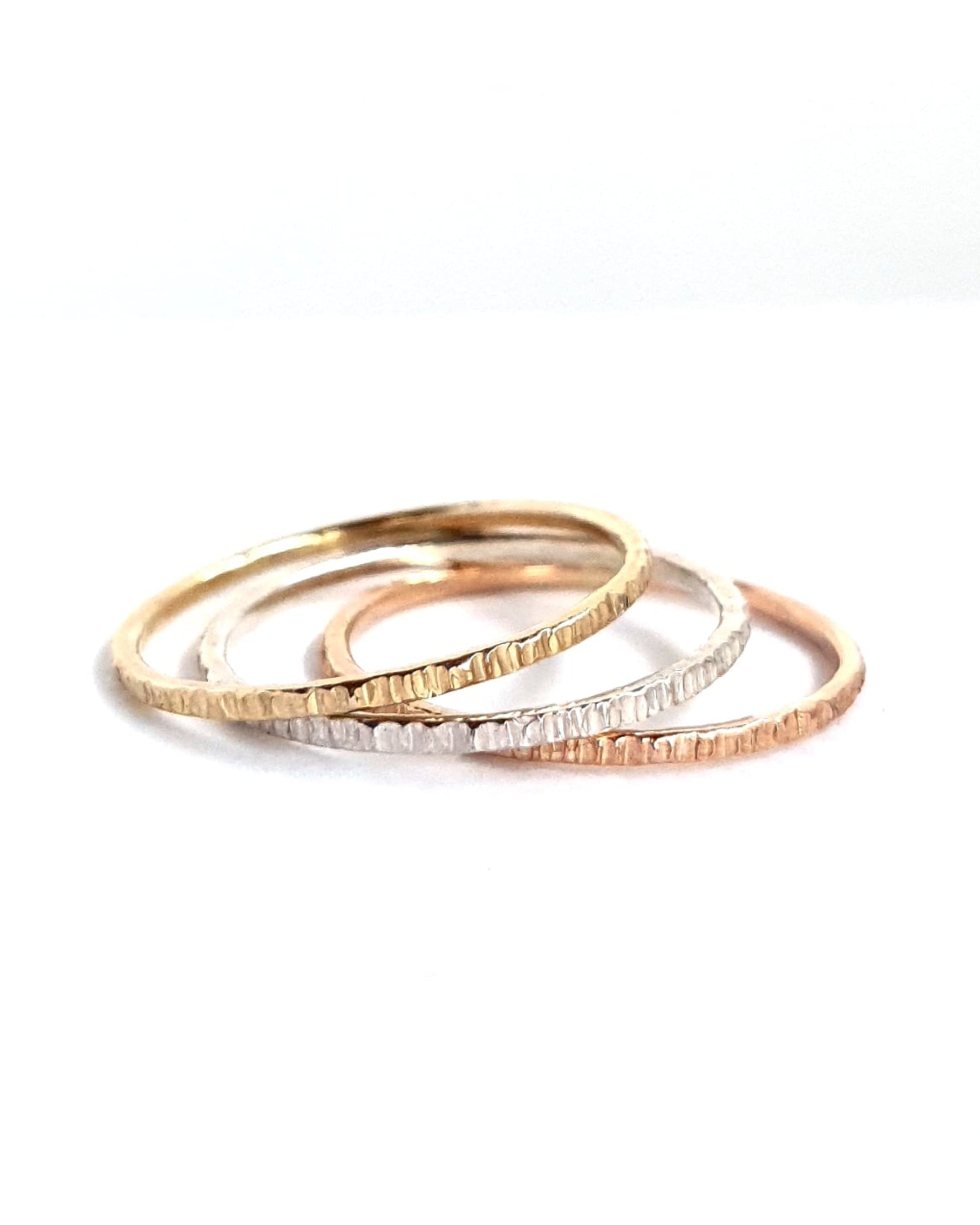 The Trinity Stack Rings, showing they are three separate rings, on a white background. These rings are a combo of Yellow Gold, Sterling Silver, and Rose Gold, and have a textured organic finish.
