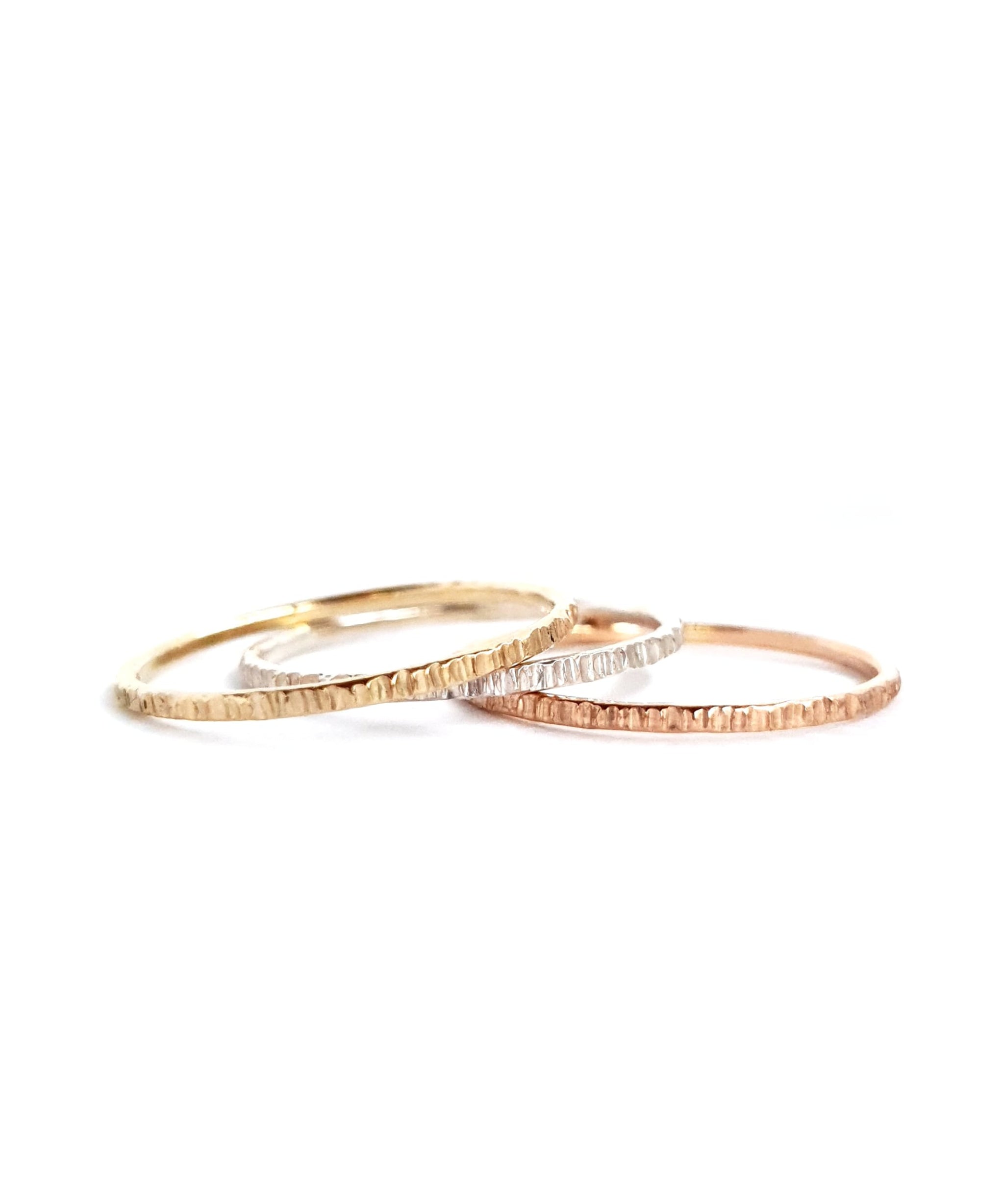 The Trinity Stack Rings, showing how they are three separate rings, on a white background. These rings are a combo of Yellow Gold, Sterling Silver, and Rose Gold, and have a textured organic finish.