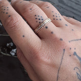 A tattooed hand wearing the Yellow Gold, Rose Gold, and Sterling Silver Stack Rings.