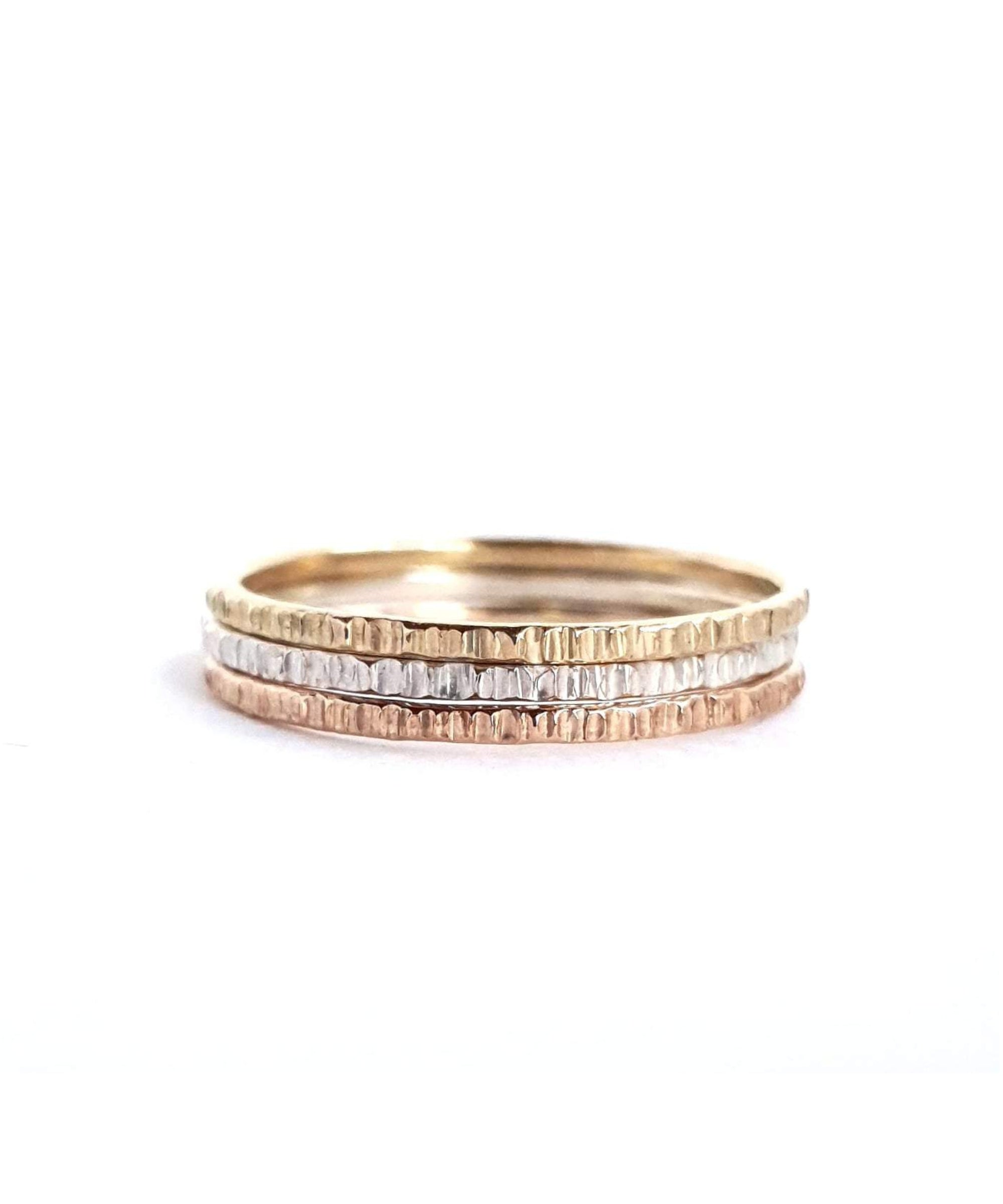 The Trinity Stack Rings on a white background. These rings are a combo of Yellow Gold, Sterling Silver, and Rose Gold, and have a textured organic finish.