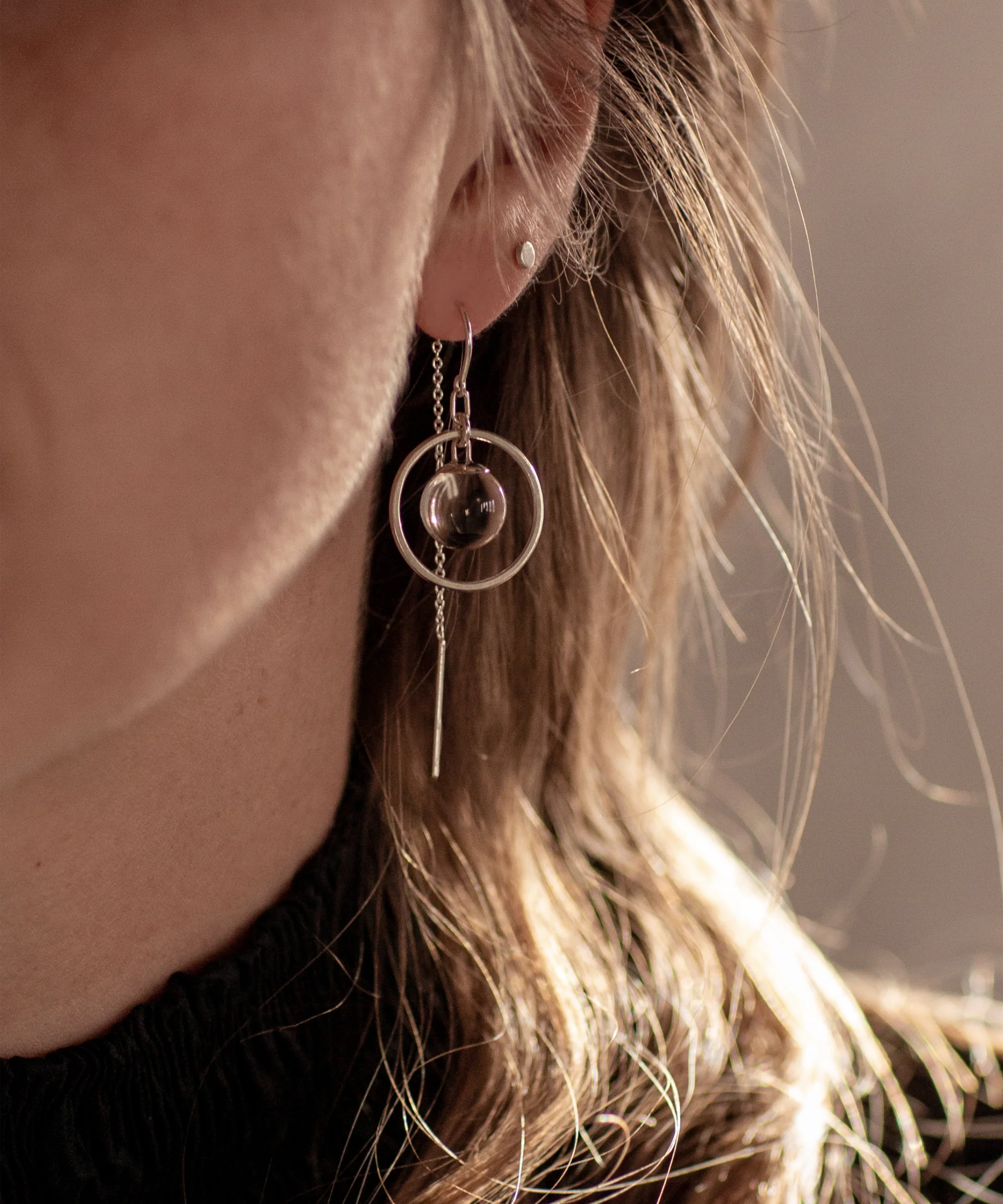 Close-up of a person wearing the Sterling Silver Divination Quartz Sphere Threader Earrings with a blurred background.