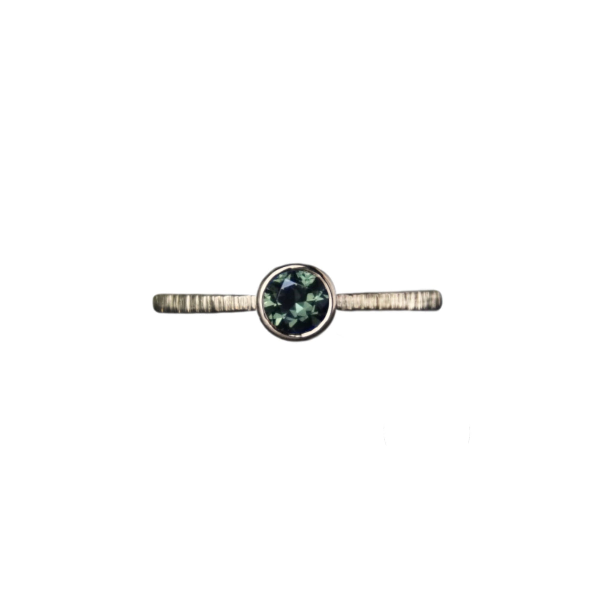 Australian Forest Green Sapphire set in an gold textured engagement ring on a white background.