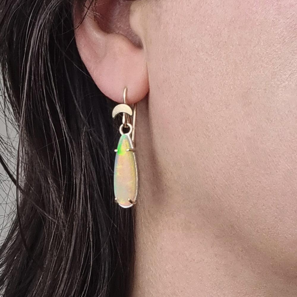 Close-up of Crystal Opal Moon Drop Earrings worn by a model, highlighting the opals' unique play of color and handcrafted design in Sterling Silver and Gold