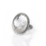 A clear Quartz oval gemstone set in sterling silver ring with an engraved halo around the setting, set on a white background.
