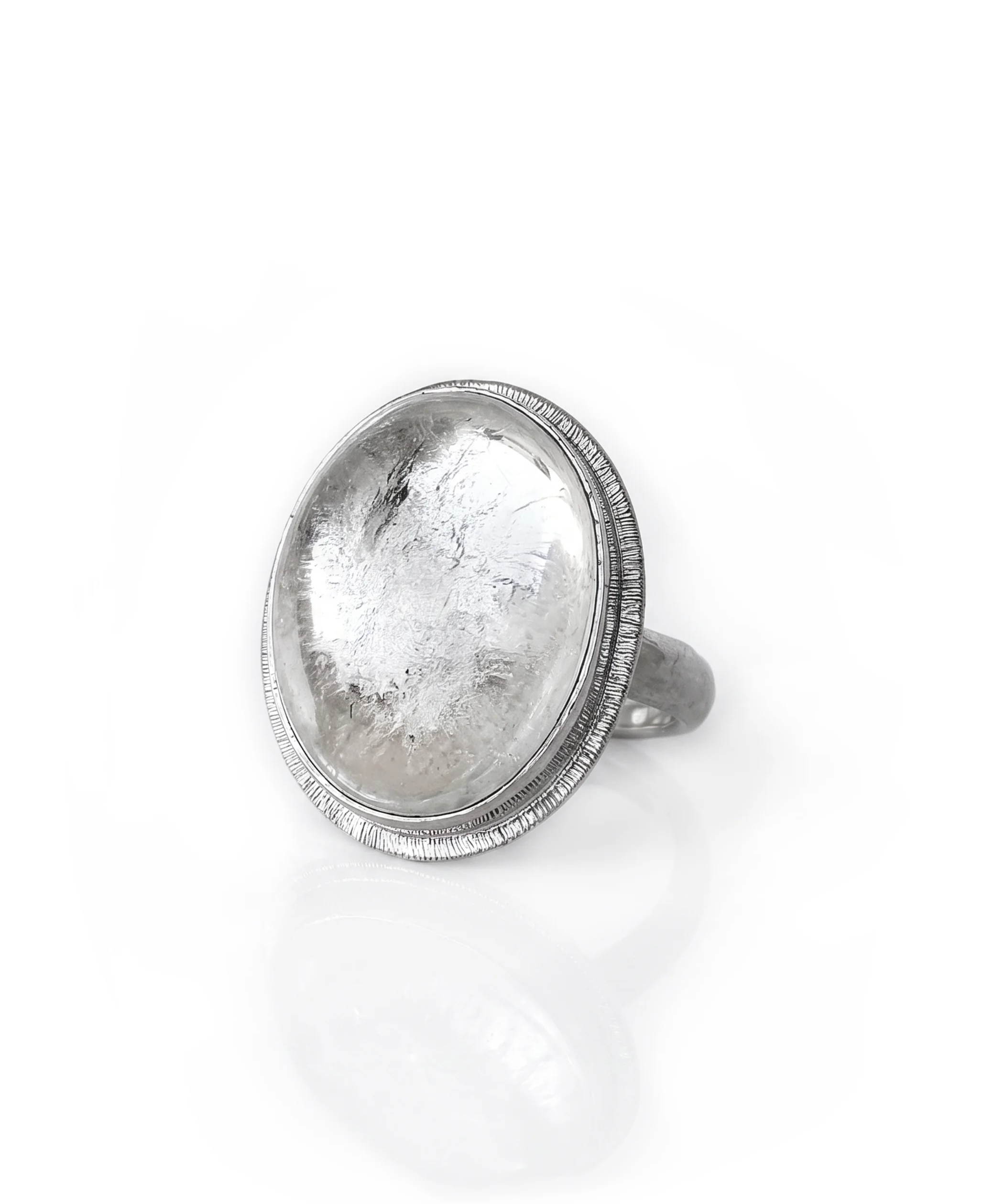 A clear Quartz oval gemstone set in sterling silver ring with an engraved halo around the setting, set on a white background.