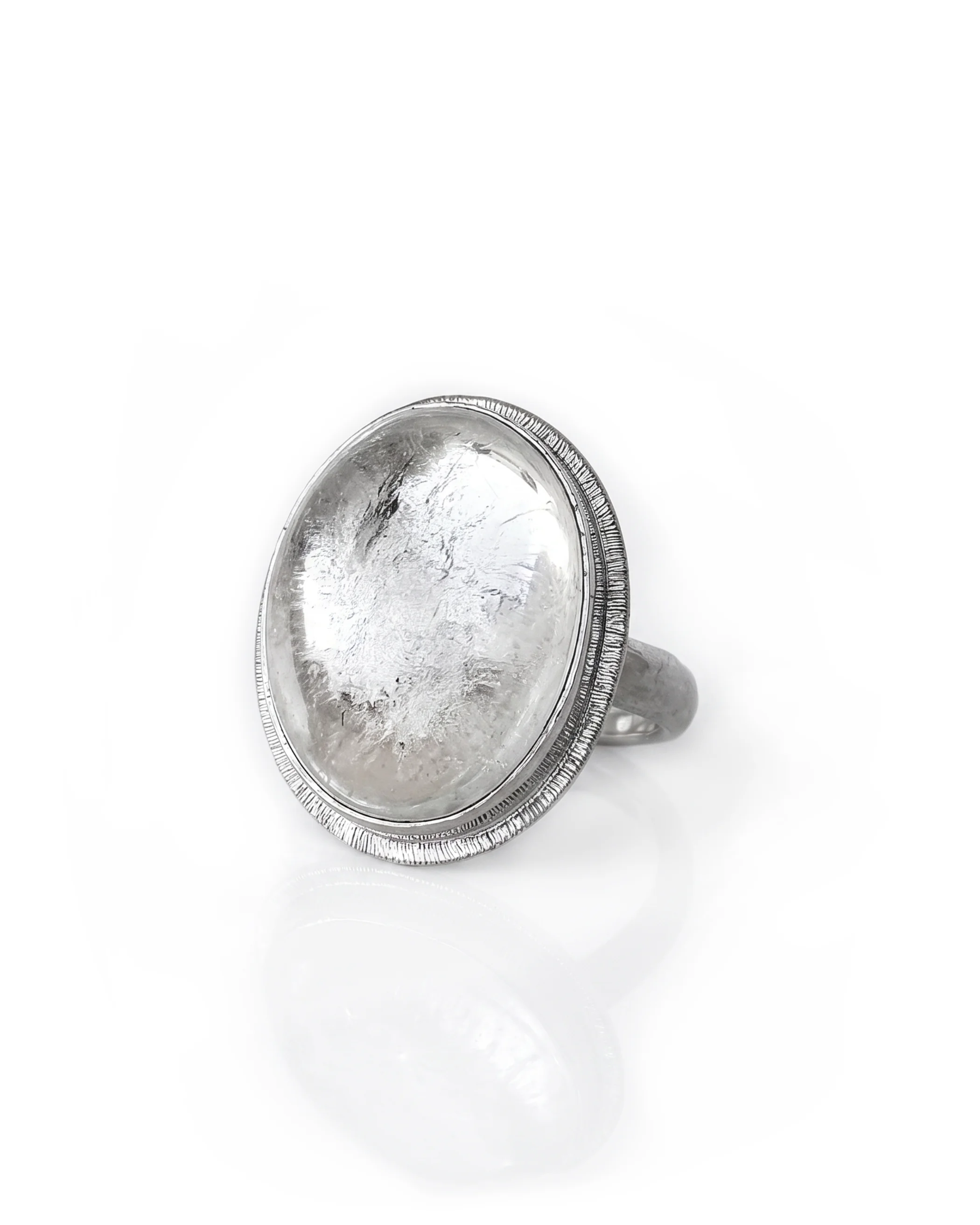 A clear Quartz oval gemstone set in sterling silver ring with an engraved halo around the setting, set on a white background.