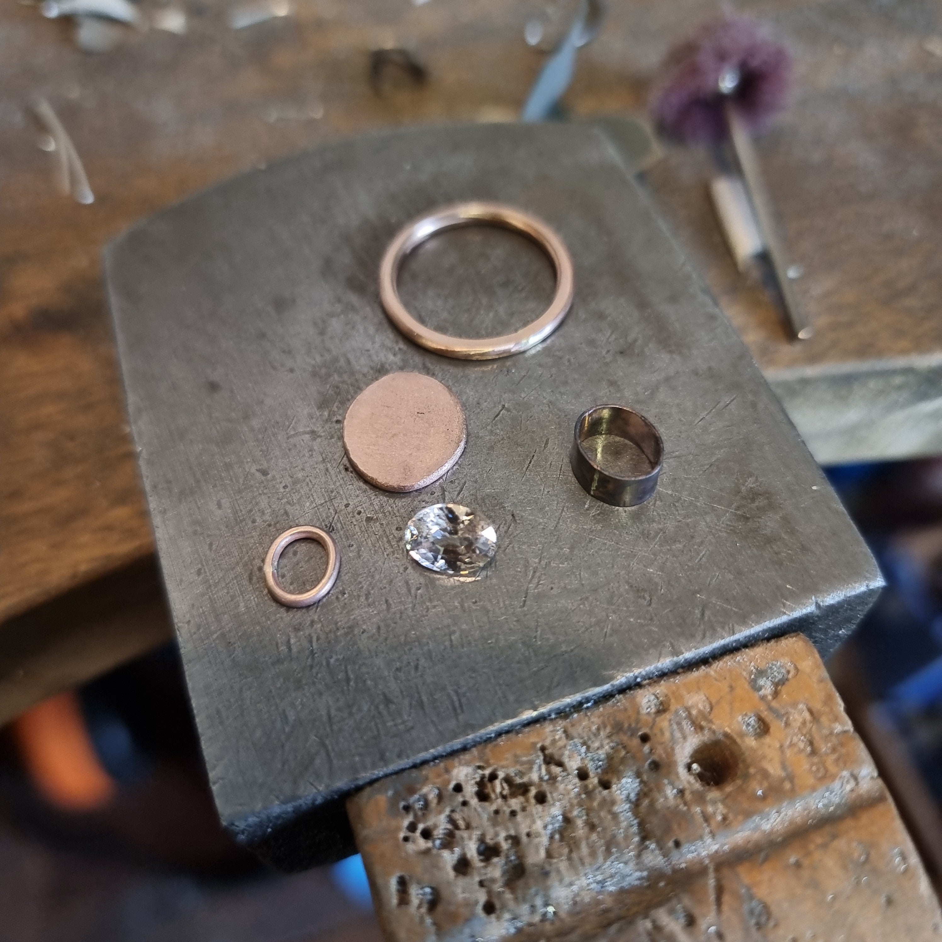 A shot a Emily Eliza Arlotte's jewellers bench peg, with handmade jewellery components on a metal anvil.