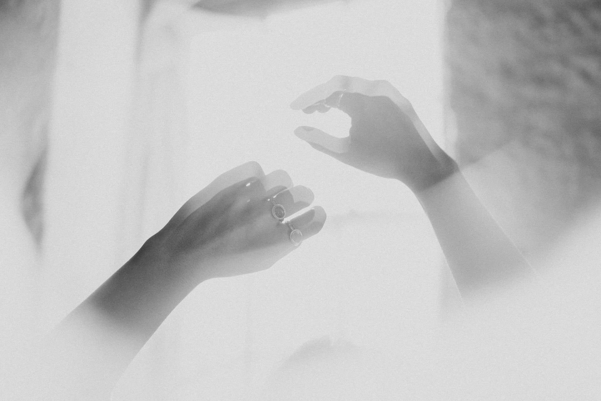Soft focus black and white image of hands dancing in front of a window wearing Australian Opal Sterling Silver rings