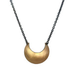 Gold Luna Crescens necklace, by Emily Elizza Arlotte, featuring a crescent moon on a black chain against a white background.