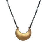 Gold Luna Crescens necklace, by Emily Elizza Arlotte, featuring a crescent moon on a black chain against a white background.