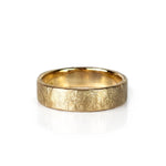 A textured yellow gold wedding band ring with a hammered, crisscrossed finish, shown on a clean white background with a soft reflection. Handmade by Emily Eliza Arlotte in Hobart, Tasmania.