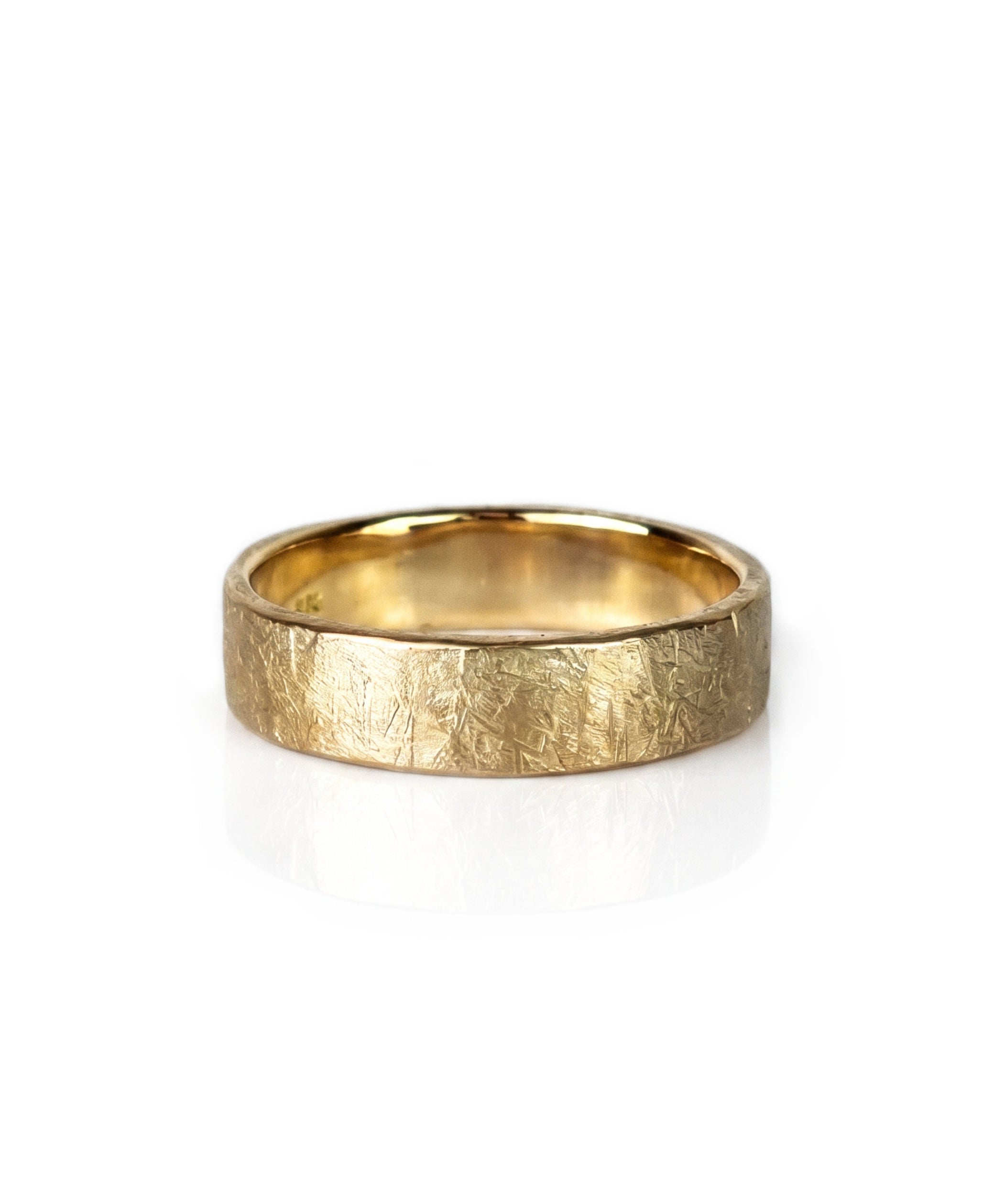 A textured yellow gold wedding band ring with a hammered, crisscrossed finish, shown on a clean white background with a soft reflection. Handmade by Emily Eliza Arlotte in Hobart, Tasmania.