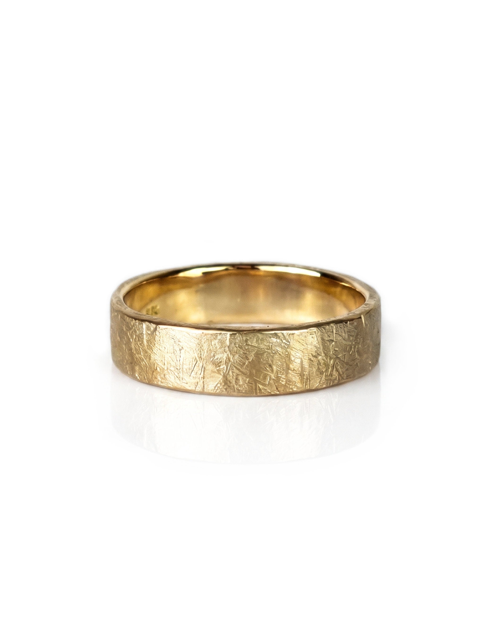 A textured yellow gold wedding band ring with a hammered, crisscrossed finish, shown on a clean white background with a soft reflection. Handmade by Emily Eliza Arlotte in Hobart, Tasmania.