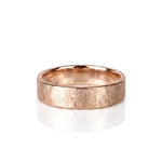 A textured rose gold wedding band ring with a hammered, crisscrossed finish, shown on a clean white background with a soft reflection. Handmade by Emily Eliza Arlotte in Hobart, Tasmania.