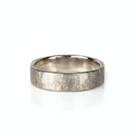 A textured raw white gold wedding band ring with a hammered, crisscrossed finish, shown on a clean white background with a soft reflection. Handmade by Emily Eliza Arlotte in Hobart, Tasmania.