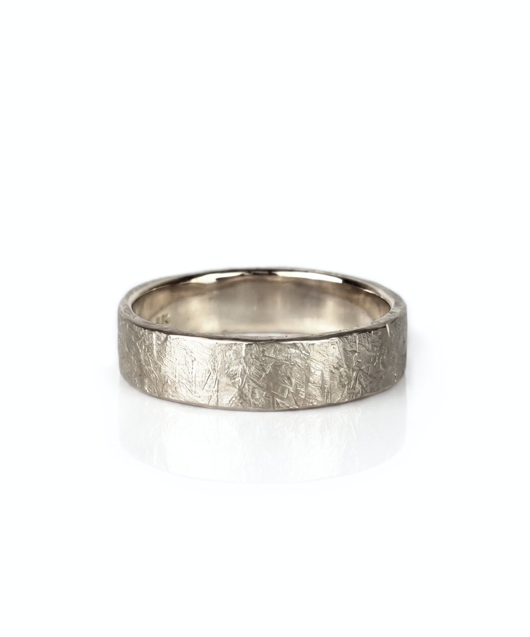 A textured raw white gold wedding band ring with a hammered, crisscrossed finish, shown on a clean white background with a soft reflection. Handmade by Emily Eliza Arlotte in Hobart, Tasmania.