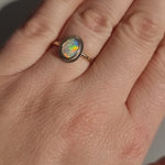 Close-up video of the Aura Gold Oval Crystal Opal Ring worn on a hand in sunlight, showcasing the opal's ethereal quality, unique transparency, and kaleidoscope of colours