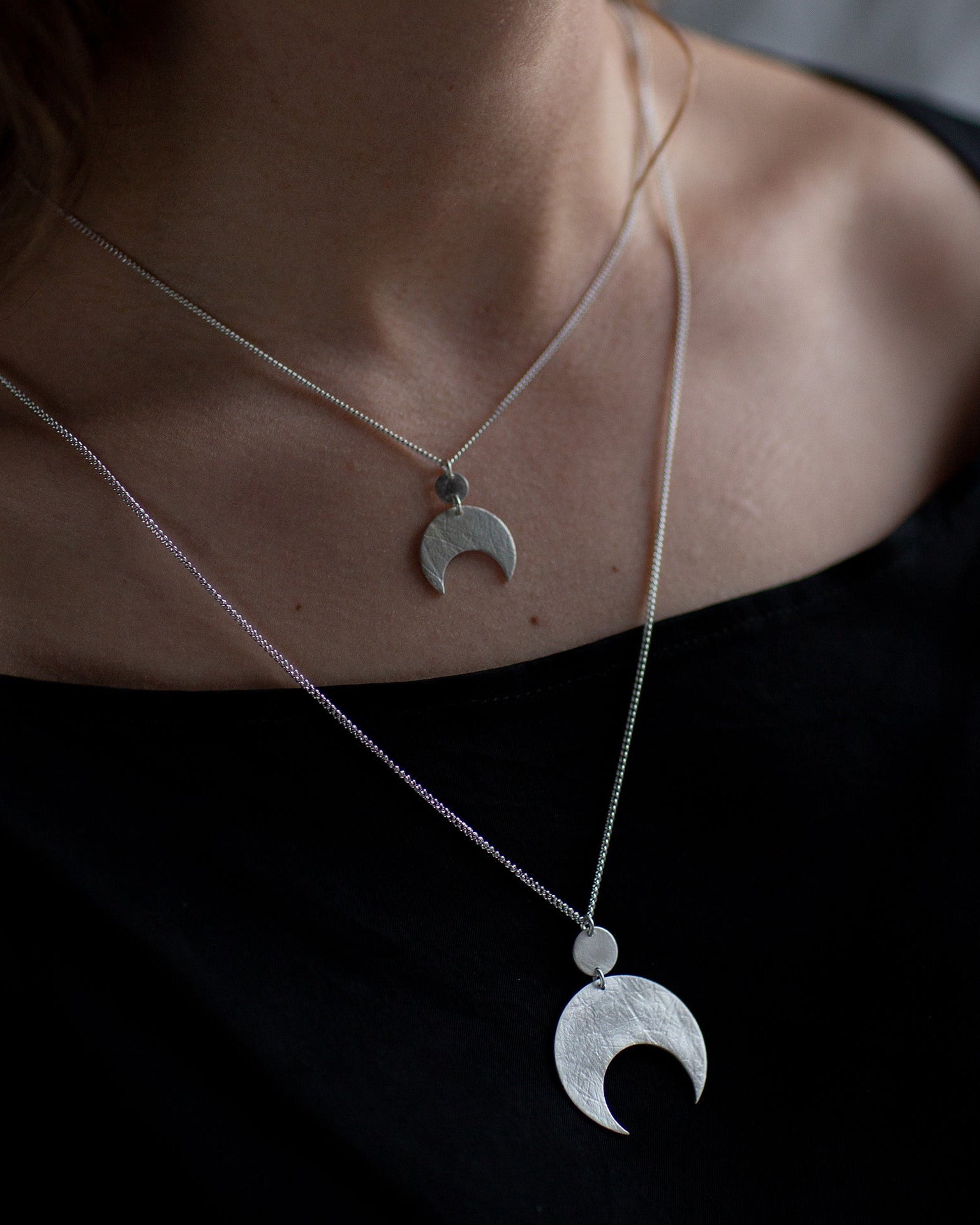 Silver necklace with moon-shaped pendants on a dark background