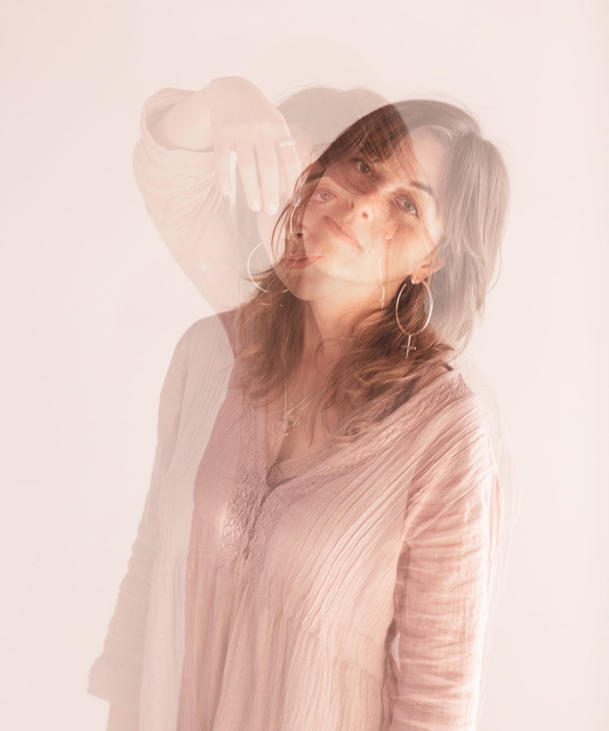 Editorial Photo shoot by Cassie Sullivan Photography of a model in soft pinkl Double Exposure movement image wearing Sterling Silver Venus Symbol Large Oversized Feminist Hoop Earrings 