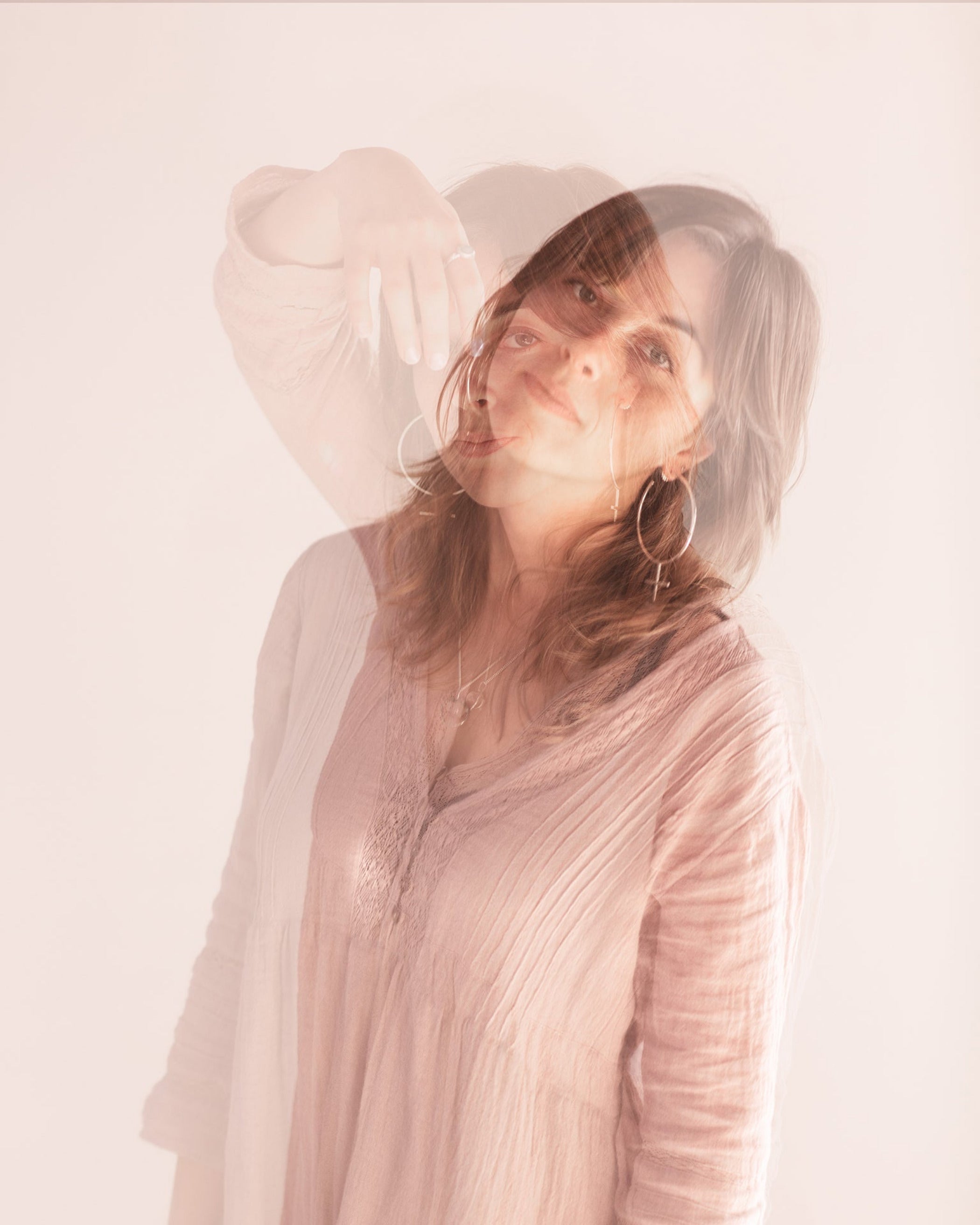 Editorial Photo shoot by Cassie Sullivan Photography of a model in soft pinkl Double Exposure movement image wearing Sterling Silver Venus Symbol Large Oversized Feminist Hoop Earrings 