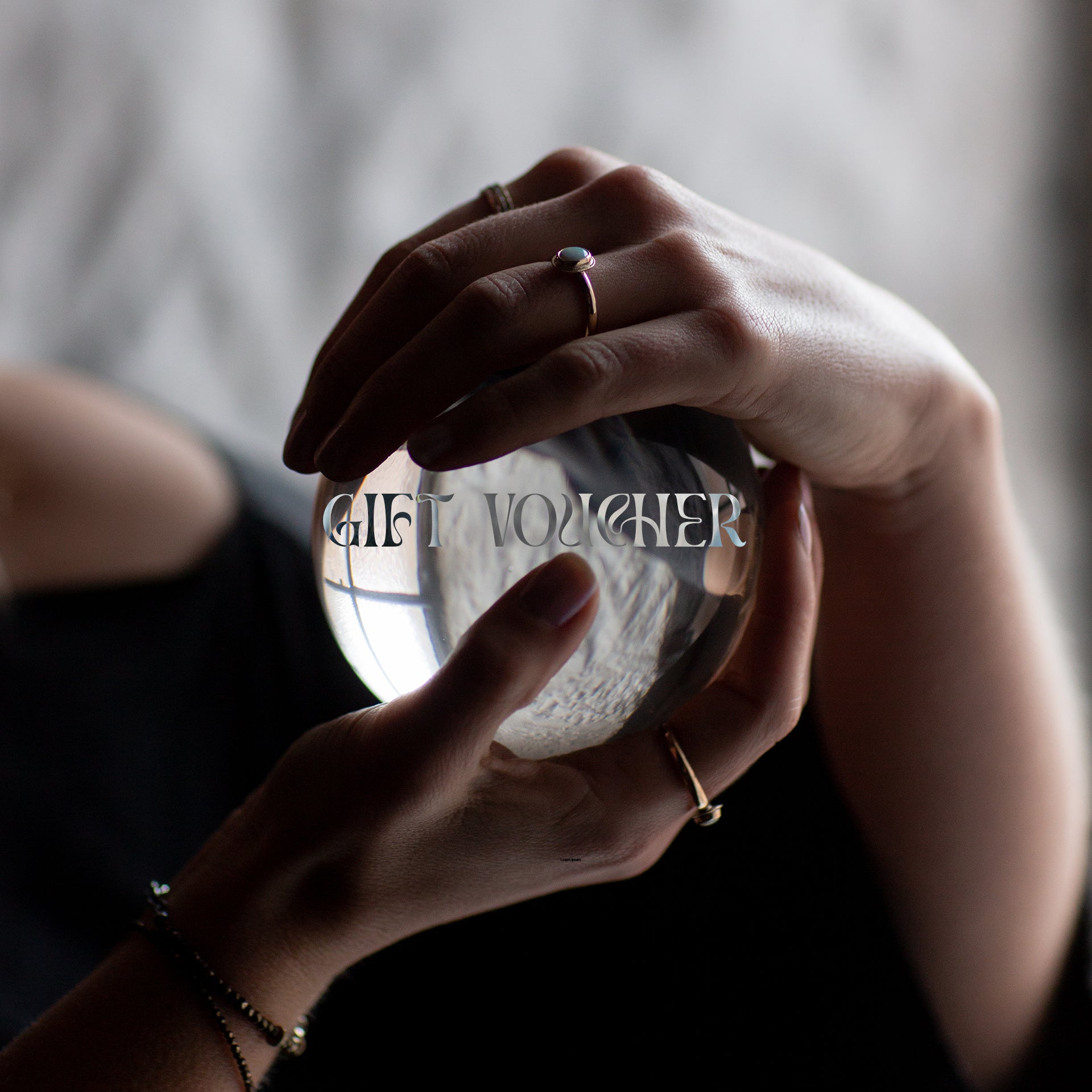 Two hands holding a crystal ball. The hadnds are wearing handmade gold and silver jewellery by Emily Eliza Arlotte, which is handcrafted in Tasmania, Australia. The crystal balls has the words GIFT VOUCHER overlayed on it.