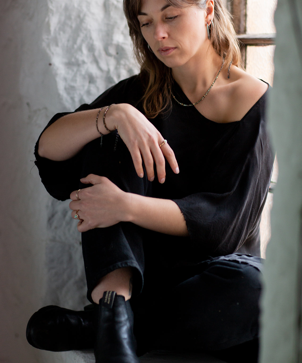  Model Eden is shown sitting in a window seal  wearing the faceted Pyrite and Gold beaded choker necklace with oxidised sterling silver chain. Handmade by Emily Eliza Arlotte in Hobart, Tasmania. Photography by Cassie Sullivan