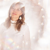 Eden wearing the Celestial Earrings and Labradorite Choker Necklace. The image, photographed by Cassie Sullivan  in an editorial style, has soft and whimsical lighting with soft pinks and reflections. Jewellery handmade by Emily Eliza Arlotte in Hobart, Tasmania.