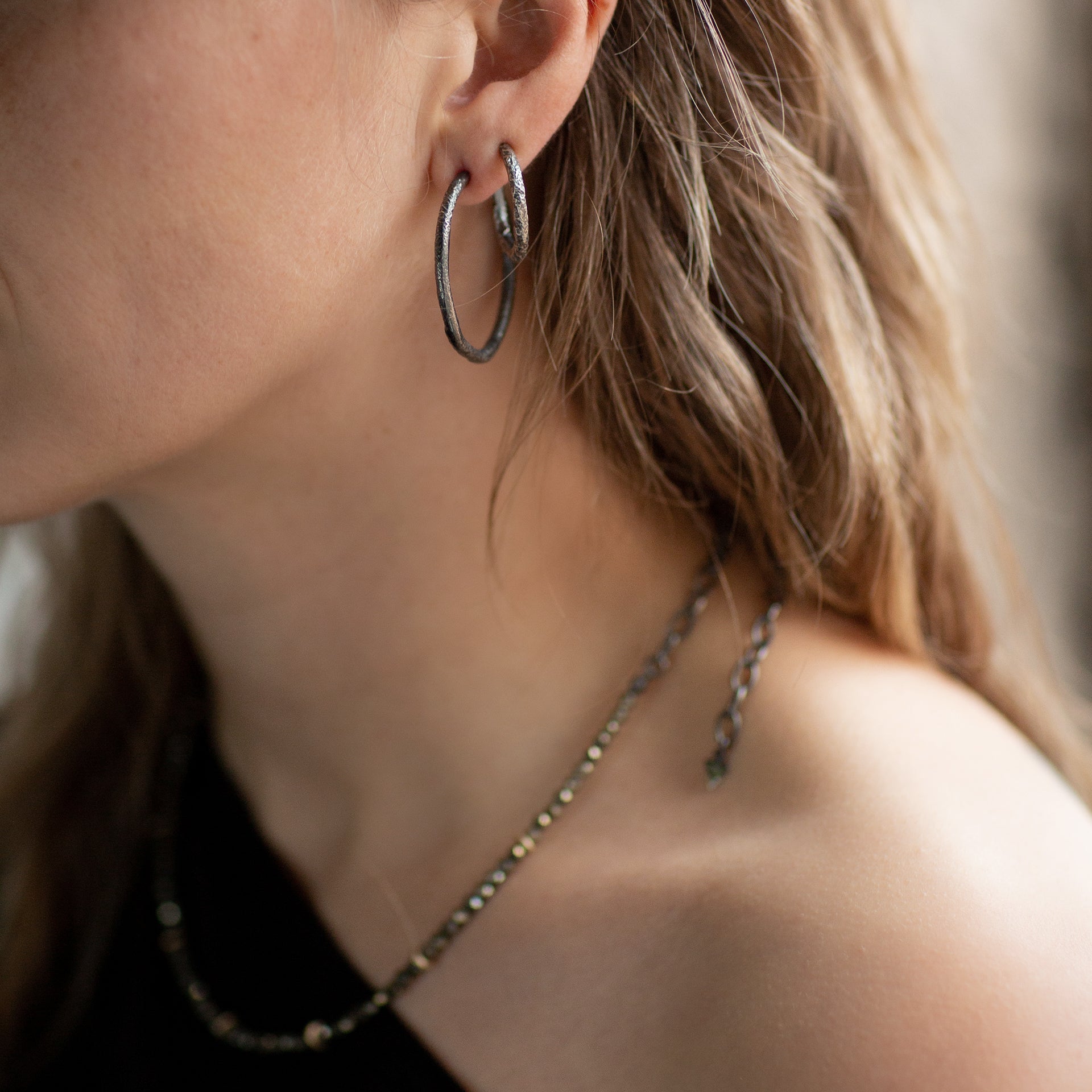 Image of the neck and jawline of model Eden earing the Oxidised Sterling Silver Reticulated Double Hoops Set and the Faceted Pyrite and Gold Beaded Choker Necklace. Photography by Cassie Sullivan.